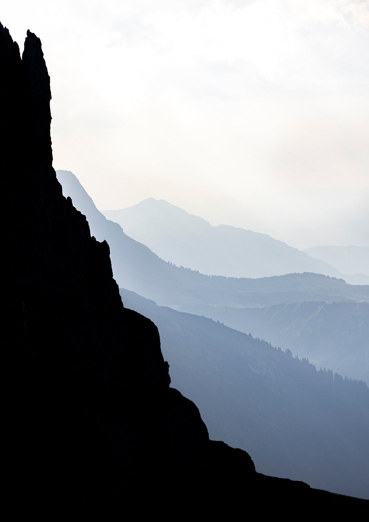 Silhouette of a mountain peak against a misty mountain range