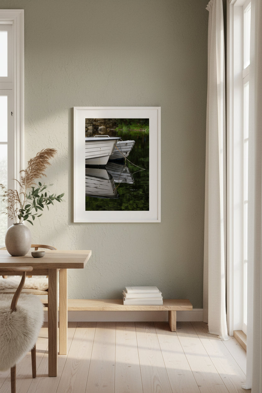 Two boats tied together on a calm body of water with reflections. Green summer landscape in Norway.