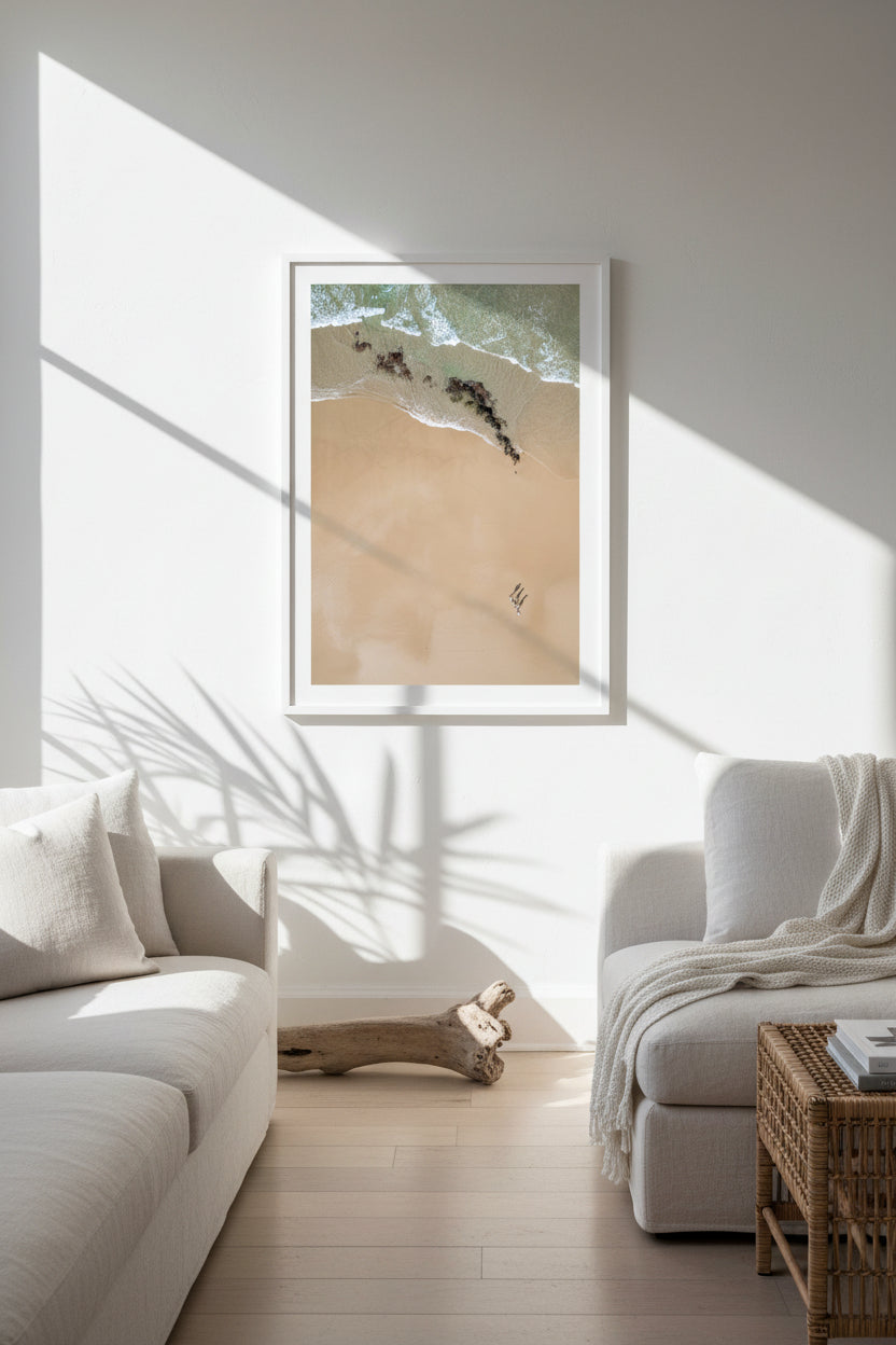 Aerial view of three people walking on a beach by the ocean.