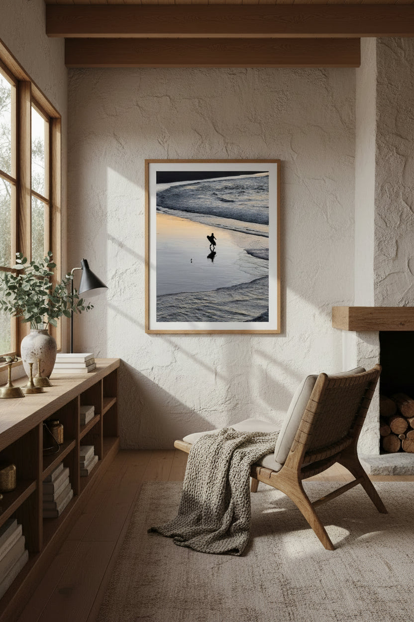 Surfer walking along a beach with waves at sunrise
